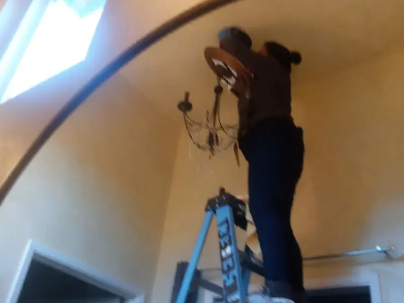 Electrician installing a chandelier in a Crestline residence